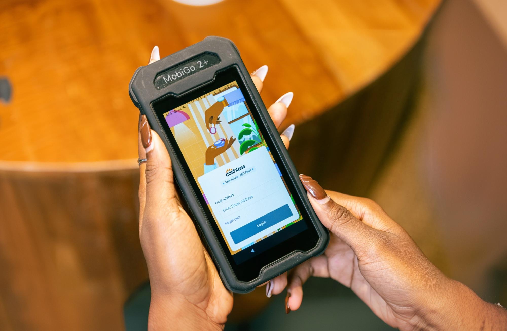 Hands holding Cashless Go with the Cashless login screen