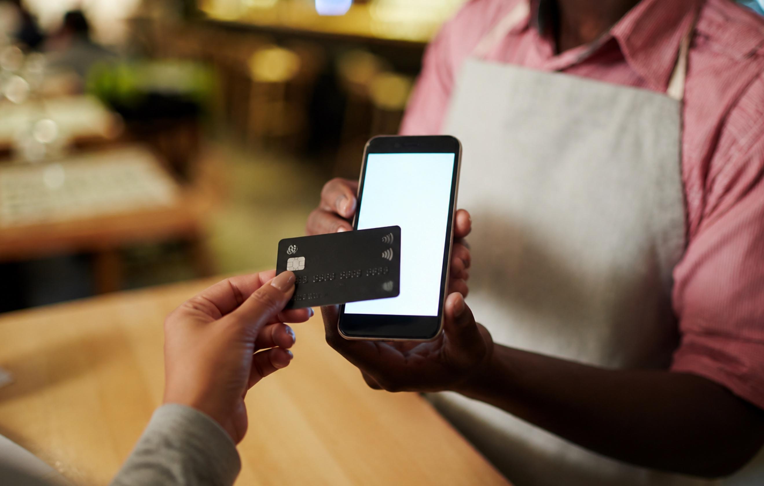 Merchant holding a phone while a customer taps a card to pay