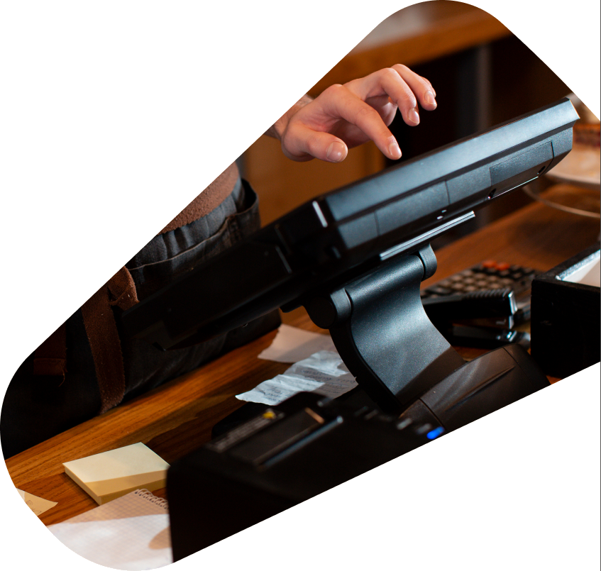 Hand using a POS touchscreen on a wooden counter